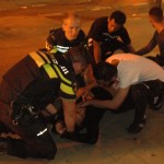 Vrienden en agenten ontfermen zich over een gewonde man tijdens rellen in de Schilderswijk. Foto: Pieter Hofmann.